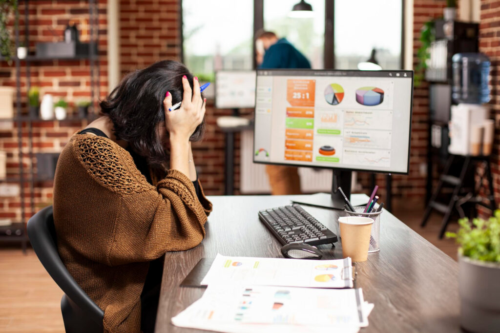Side view of a stressed women working on a laptop outdoors, with the screen displaying a marketing campaign dashboard showing zero leads and poor results.